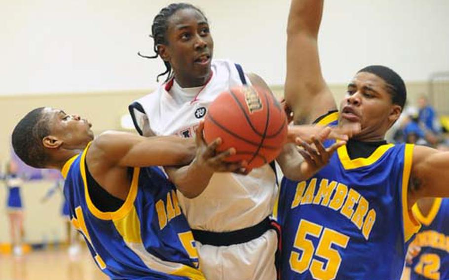 Aviano's Jamal Tuck draws a fouls as he drives between Bamberg's Joshua Robinson, left, and Cortez Lindsey. Aviano beat the Barons 85-59 to win the Division II championship at the DODDS-Europe basketball finals in Mannheim, Germany, Saturday night.