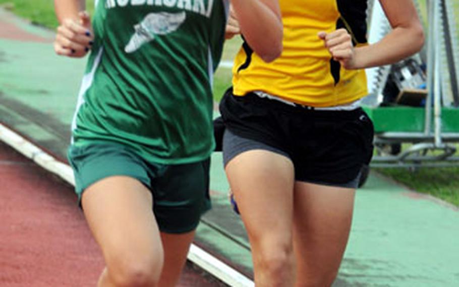 Kubasaki freshman Jessica Powell passes Kadena senior Britni Dougherty on the fourth lap of the girls&#39; mile race. Powell won in 6 minutes; Dougherty was second in 6:10.