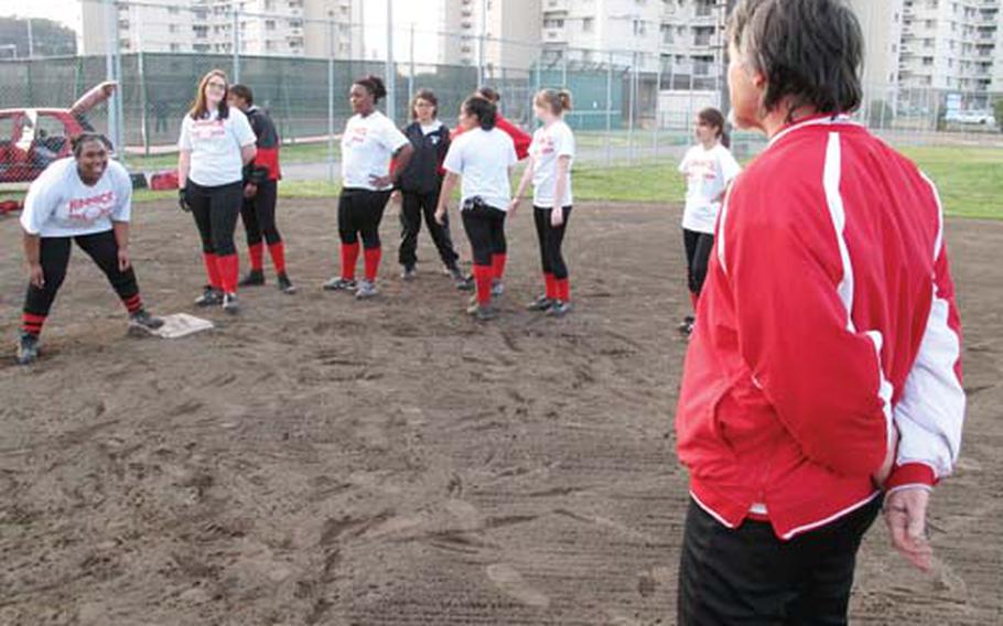Sixth-year Nile C. Kinnick Red Devils softball coach Danel MacWhyte, right, conducts a baserunning drill during Tuesday&#39;s practice.