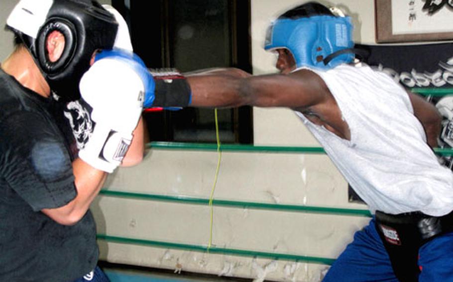 Petty Officer 2nd Class Albert King of the Yokosuka Naval Base, Japan, security department spars with a local boxer at the Rodeo Style, an off-base gym.