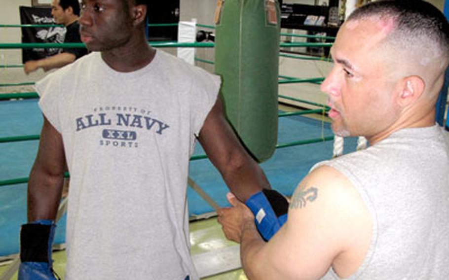 Seaman Nelson Tatis helps Petty Officer 2nd Class Albert King with his boxing gloves.