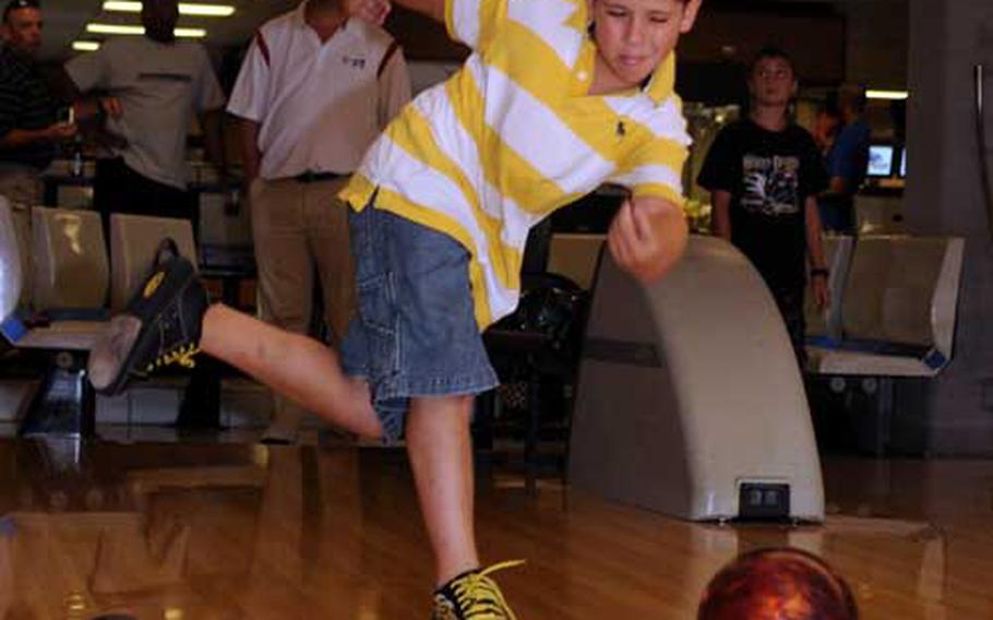 9-year-old Caedon McClendon delivers under the watchful eye of Professional Bowling Association pro Patrick Allen, rear, during Friday&#39;s youth clinic at Emery Lanes, Kadena Air Base, Okinawa. Allen and fellow PBA-er Randy Pedersen hosted the clinic.