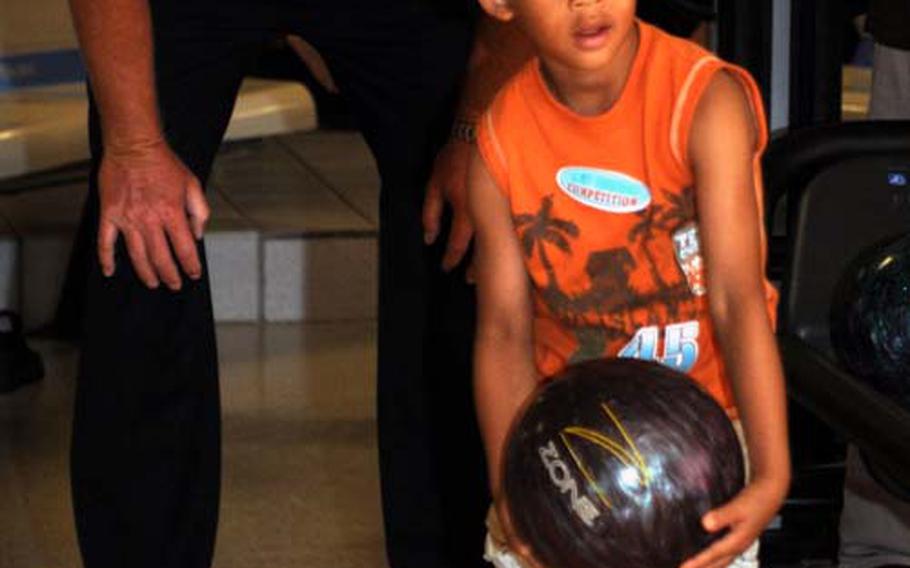 4-year-old C.J. Hall prepares to deliver under the watchful eye of Professional Bowling Association pro Randy Pedersen, rear, during Friday&#39;s youth clinic at Emery Lanes, Kadena Air Base, Okinawa. Pedersen and fellow PBA-er Patrick Allen hosted the event.