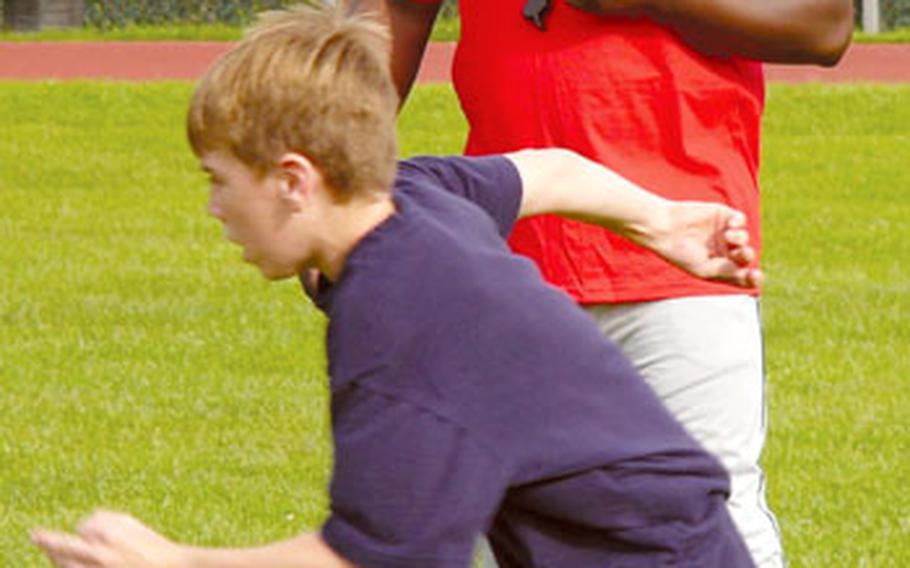 Volunteer youth tackle football coach Darryl Harris runs 12-year-old Krystian Abbott of Sembach, who said he’s played tackle football in five different states, through a drill at a recent clinic in Landstuhl.