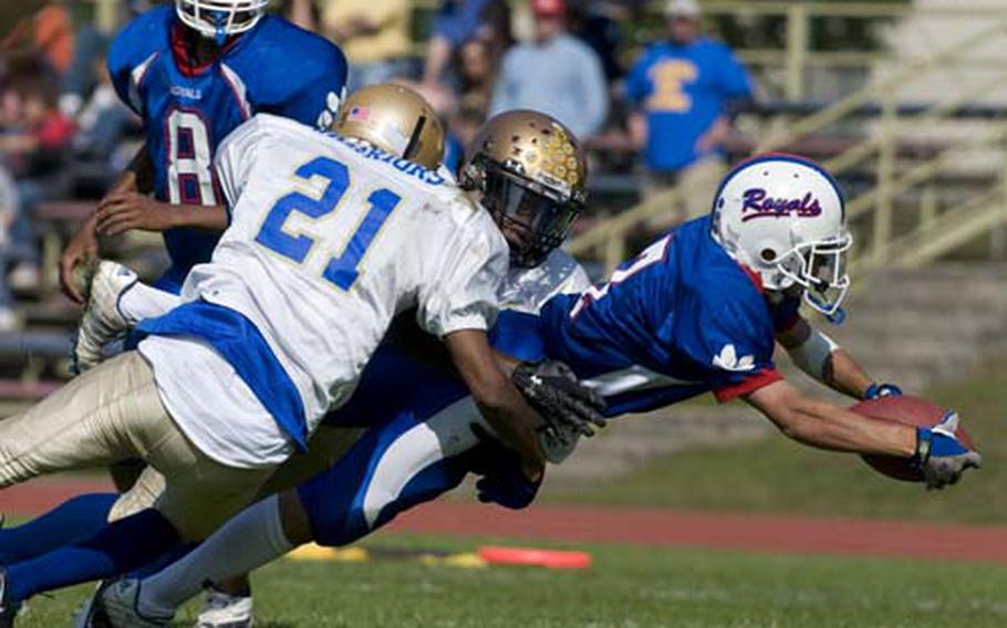 Ramstein running back Aaron Salcido stretches for extra yardage while being brought down by Wiesbaden defenders during the Royals’ 55-12 Division I football victory Saturday. Salcido caught touchdown passes of 28, 12 and 23 yards from quarterback Michael Wallace.