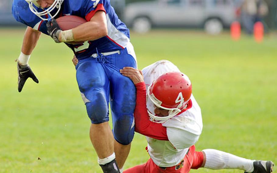 Ramstein&#39;s Will Canfield, left, escapes the grasp of Kaiserslautern&#39;s Hanawa Hampton on his way to scoring one of his three touchdowns in the Royals 49-0 win over Kaiserslautern on Saturday.