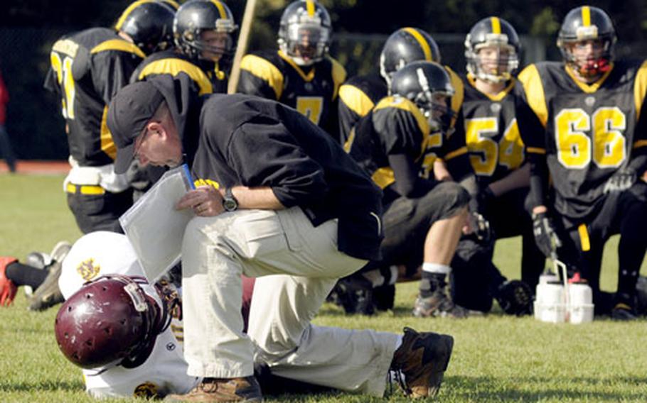 Patch head coach Brian Hill checks on an injured Vilseck player while his team kneels behind him.