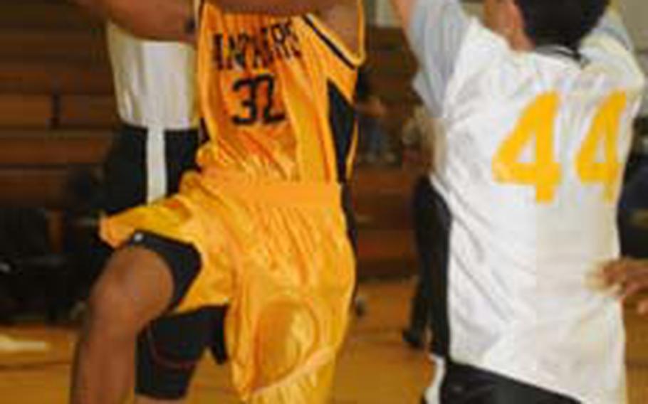 Kadena Panthers senior guard Taiyo Robertson (32) knifes between two Koza defenders to the basket during Friday&#39;s high school boys basketball season opener at Panther Pit, Kadena HIgh School, Kadena Air Base, Okinawa. Robertson scored 28 points, 13 in the first quarter, as Kadena routed Koza 92-58.