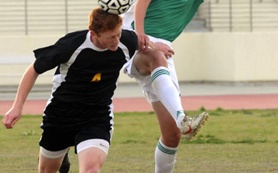 Kadena's Stanley Schrock (4) heads the ball away from a leaping Zach Stallings (12) of Kubasaki during Friday's soccer match at Kadena Air Base, Okinawa. Kadena won 5-1.