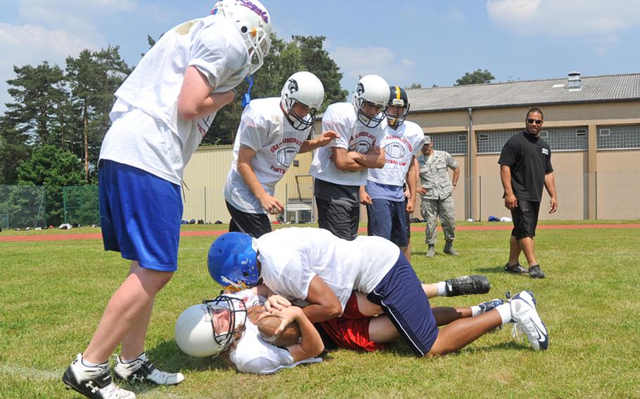 Arizona Cardinals running back Reagan Maui?a, right, and camp participants watch John Bradley of Bamberg, top, pull down Codey Nygren of  Kaiserslautern, during a drill on Thursday. More than 140 players participated in the camp in Miesau, Germany.