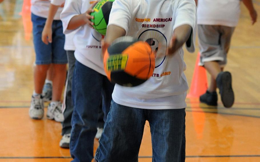 Cameron Simpson, 7, aims for the basket as he takes an underhand shot during a basketball workshop at the Mannheim Community?s one-day German-American sports camp at Benjamin Franklin Village and Sullivan Barracks. About 400 youngsters turned out for the camp on Friday that featured basketball, soccer, lacrosse, archery and American football workshops.