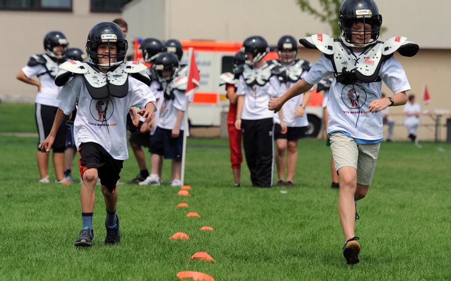 Participants run a 40-yard dash in pads and helmets at the Mannheim Community?s one-day German-American sports camp at Benjamin Franklin Village and Sullivan Barracks. About 400 youngsters turned out for the camp on Friday that featured basketball, soccer, lacrosse, archery and American football workshops.