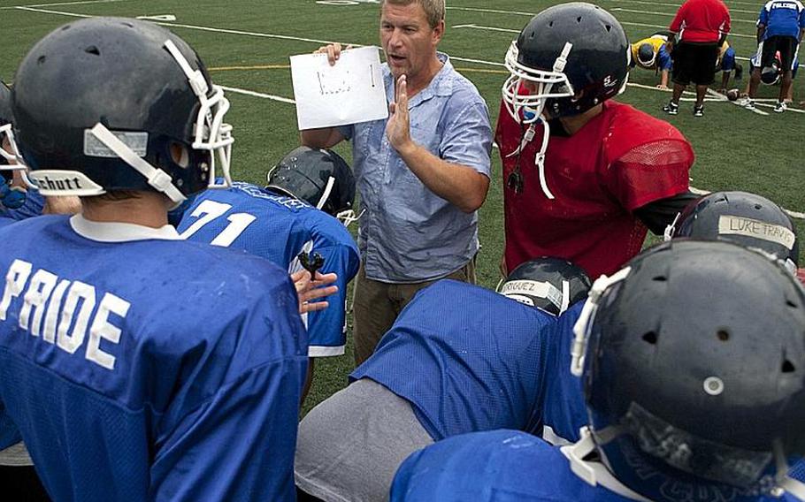 New head coach Billy Ratcliff calls a play in the huddle during Wednesday&#39;s Seoul American Falcons football practice at Sims Field, Seoul American High School, South Post, Yongsan Garrison, South Korea.