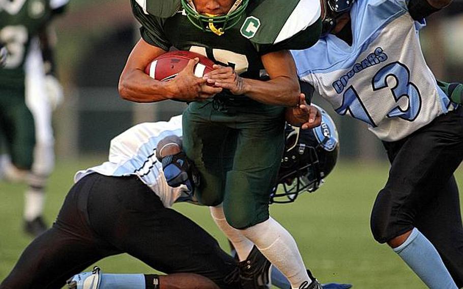 Ryan Banzon of Daegu American slices with the ball between Osan American defenders Edward Moore, right and Dominique Williams during Friday's DODDS Korea football game at Kelly Field, Camp Walker, South Korea. Daegu routed Osan 42-6.