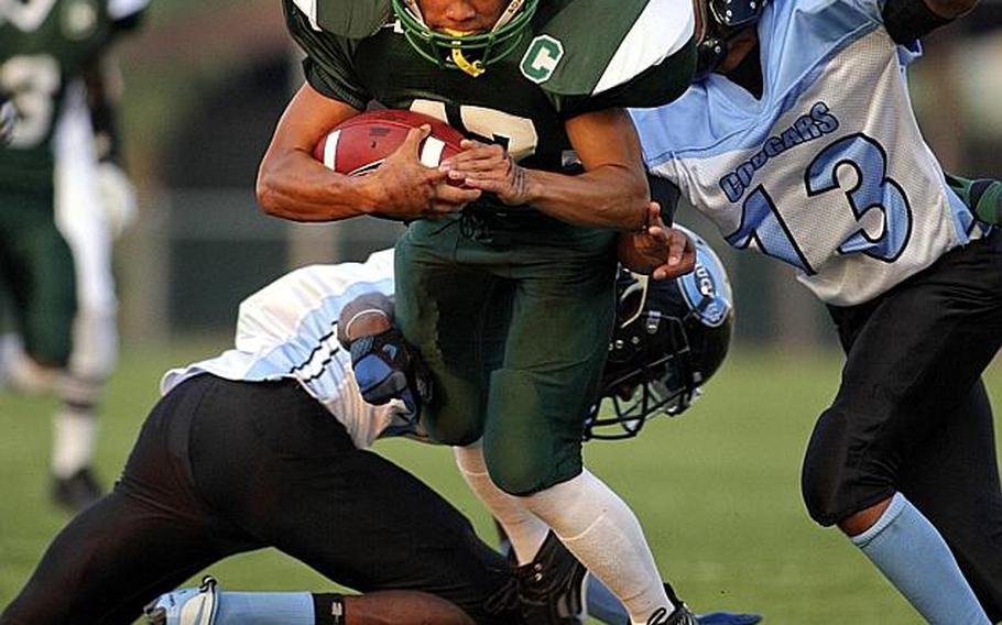 Ryan Banzon of Daegu American slices with the ball between Osan American defenders Edward Moore, right and Dominique Williams during Friday&#39;s DODDS Korea football game at Kelly Field, Camp Walker, South Korea. Daegu routed Osan 42-6.