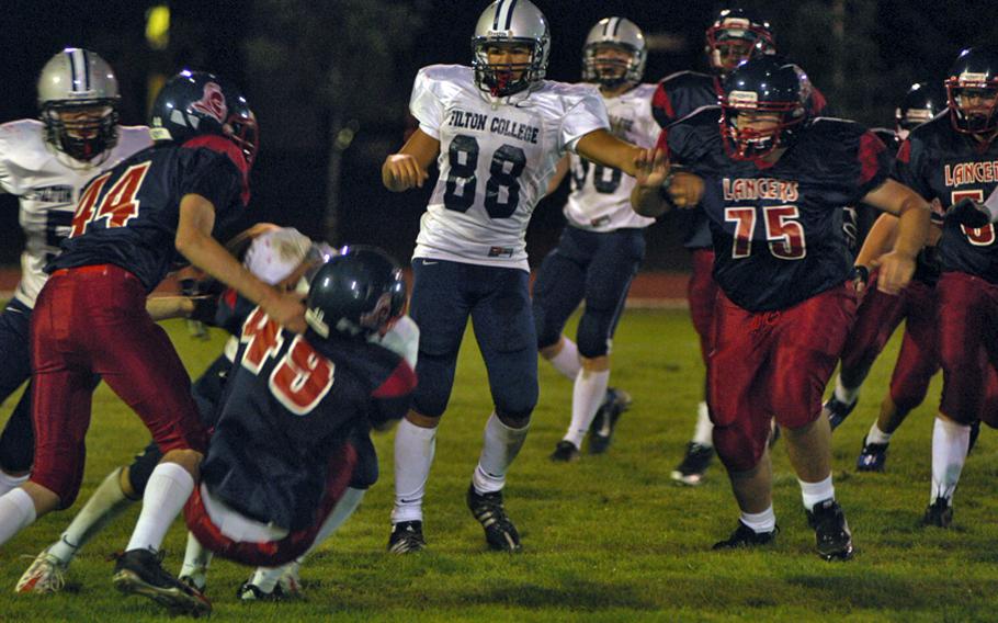 Lakenheath defenders Jourden Wilson (49)  and Trey Abrego (44) tackle Filton Academy running back Cameron Parker while Filton's Jordan Eaton and Lancer defensive tackle Dustin Rollings, senior, close in on the play during a 31-6 loss to the Pride, Sept. 17, at RAF Lakenheath, England.