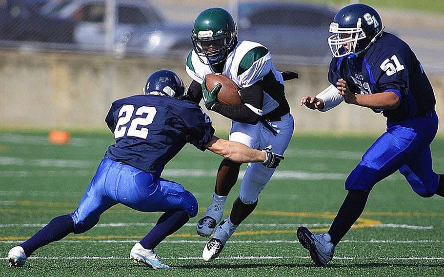 Jalah Patten of Kubasaki eludes the tackle of Seoul American&#39;s Tanner McQueen (51) and Matthew Choi (22) in Saturday&#39;s interarea high school football game at Sims Field, Seoul American High School, South Post, Yongsan Garrison, South Korea. Kubasaki won 31-6.