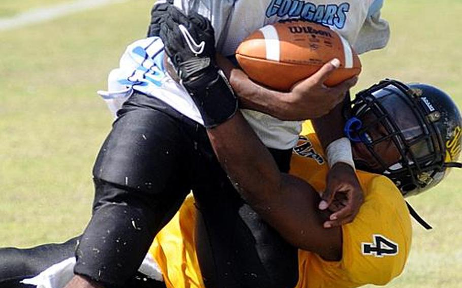 Osan American Cougars ball carrier Devin Turner gets hauled down by Kadena Panthers defender Rodney Goodson during Saturday's interarea high school football game at Ryukyu Middle School, Kadena Air Base, Okinawa. The host Panthers routed the Cougars, 46-8.