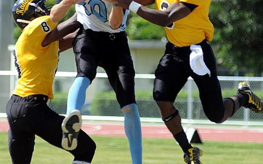 Osan American Cougars receiver Michael Benson hauls in a pass between Kadena Panthers defenders Tyrell Crutcher, left, and Shariff Coleman during Saturday's interarea high school football game at Ryukyu Middle School, Kadena Air Base, Okinawa. The host Panthers routed the Cougars, 46-8.