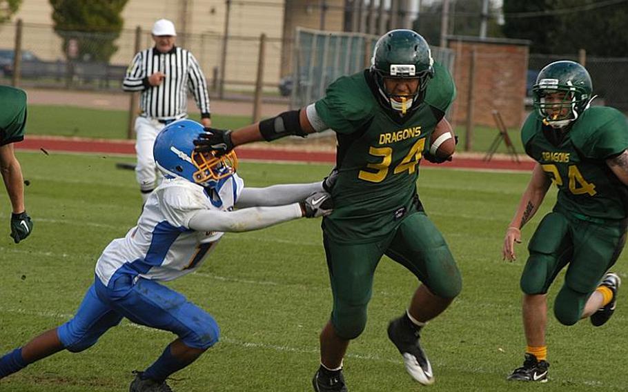 Alconbury's Kerry Kuheana gives a stiff arm to Sigonella defender Marco Montero during a double overtime victory for the Dragons at home. Kuheana had 296 total yards during the game, won 26-20, by Alconbury.