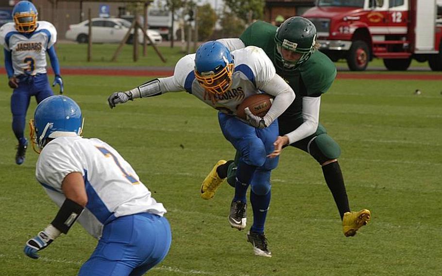 Alconbury defensive end Sabastien Schniebs wraps up Sigonella running back Jeff Lastrella while Marco Summerfield prepares to block an oncoming Dragon.