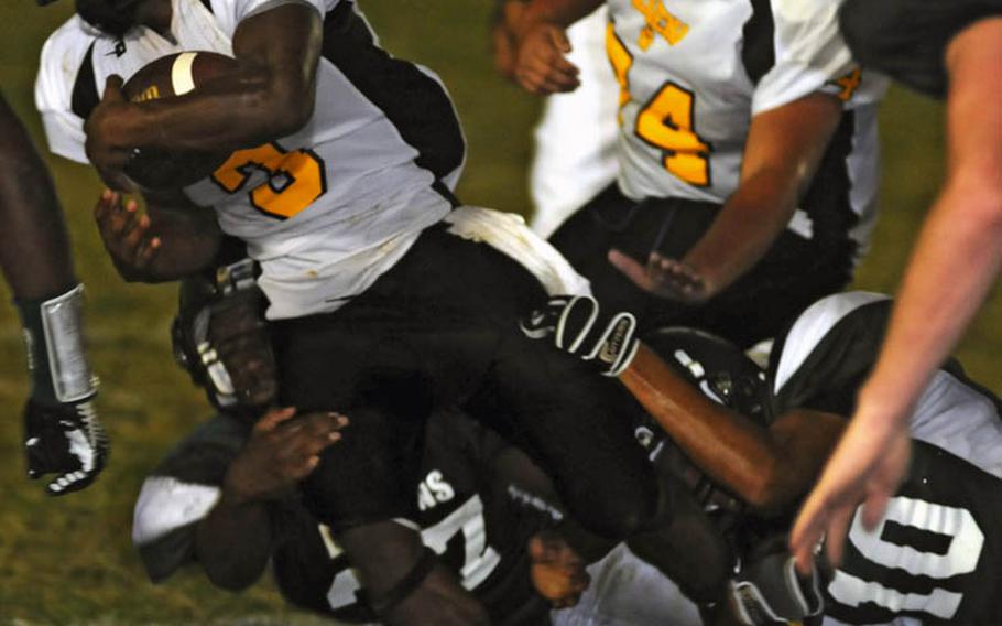 Kadena running back Shariff Coleman tries to slither out of the tackle of Kubasaki's Terry Bakewell and Rolando Hernandez during Friday's Okinawa Activities Council football game at Mike Petty Stadium, Kubasaki High School, Camp Foster, Okinawa. Kadena routed Kubasaki, 56-16.