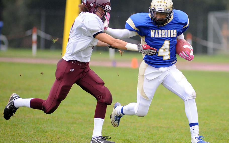 Wiesbaden's Daniel Harris, right, straight arms Vilseck's Darius Whitehead on his way to a big gain in a Division I -South match up in Wiesbaden, on Saturday. Harris scored two touchdowns in the Warriors' 34-7 win over the Falcons.