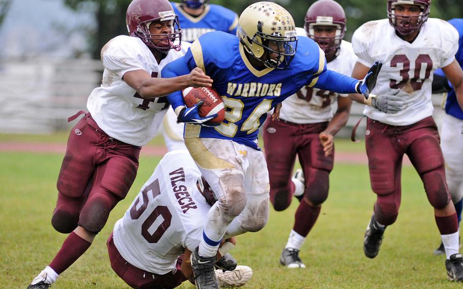 Wiesbaden's Tevin Teal carries the ball upfield as Vilseck's Dennis Thomas, left, and Keenan Massey try to bring him down. The Warriors won the game against visiting Vilseck, 34-7.