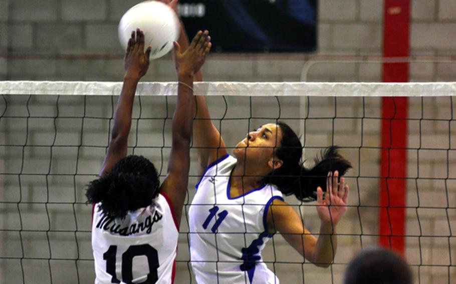 Rota's Gabriella Rivera spikes the ball while Menwith Hill defensive player Alexis Thomas attempts to block the strike.