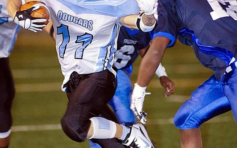 Osan American's Paul Snead tries a stiff arm as Seoul American's Antoine Daniels gives chase during Friday's DODDS Korea high school football game at Sims Field, Seoul American High School, South Post, Yongsan Garrison, South Korea. The Falcons won their first game of the season, 41-6, over the Cougars.