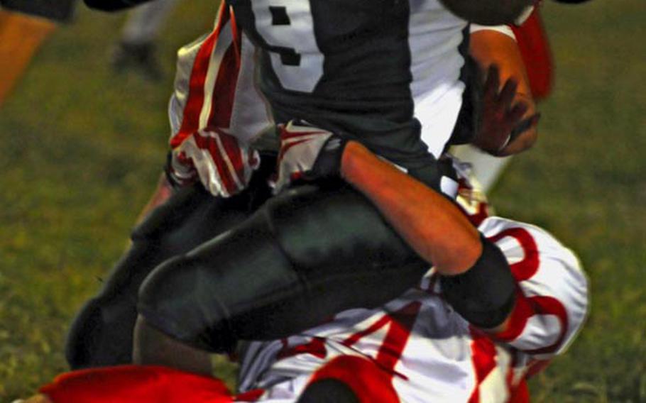 Kubasaki Dragons senior running back Deon Lewis gets wrestled to the ground by Nile C. Kinnick Red Devils defender Dustin Kimbrell during Saturday's Far East Division play-in game at Mike Petty Stadium, Kubasaki High School, Camp Foster, Okinawa. Kubasaki qualified for the Division I playoffs by routing Kinnick, 37-6.