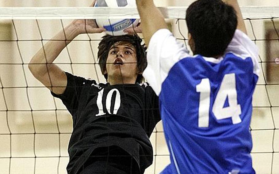 Osan American's Billy Bortscheller, left, looks for a spot to send the ball as Seoul American's Michael Rivera goes up to block during Friday's Korean-American Interscholastic Activities Conference boys volleyball match at Cougars Gymnasium, Osan American High School, Osan Air Base, South Korea. Osan won 25-10, 21-25, 25-17, 22-25, 15-9 to remain unbeaten through 12 matches in the KAIAC Division I season. The Cougars are going for a school-first unbeaten season and KAIAC regular-season and tournament title.