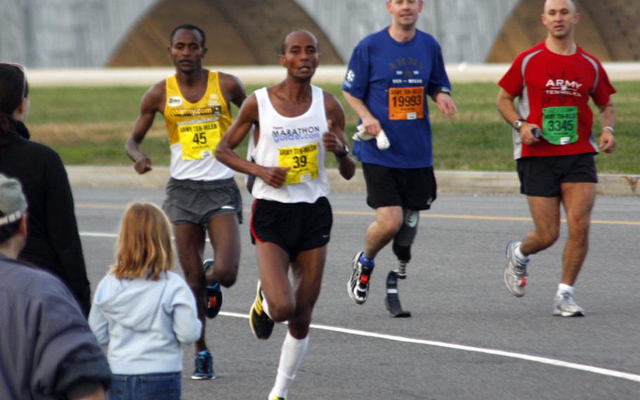 Wounded Warrior runners Bruce Gannaway (19993) and  Eric Wolf (3345) watch as Alene Reta and Tesfaye Sendeku open up a lead on the rest of the field.