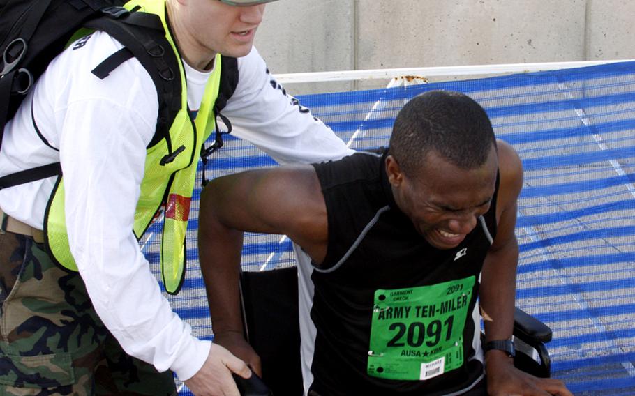 Rohan Knight of St. Albans, N.Y., is assisted after finishing the race. Knight was timed in 1:14.21.
