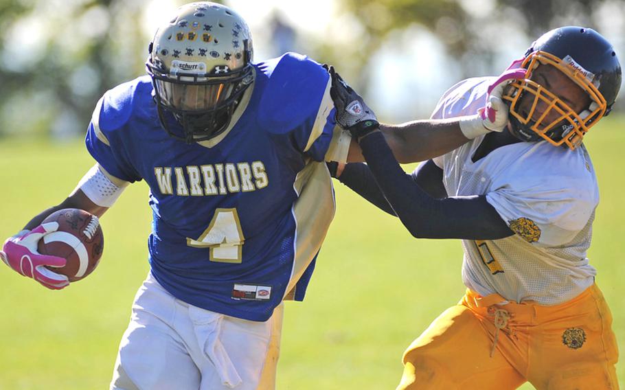 Wiesbaden's Daniel Harris keeps Heidelberg defender Sterling Jones at arm's  length as he picks up yardage in the Division I game in Wiesbaden, on Oct. 9. His efforts were for naught, as the Lions beat Wiesbaden, 54-19, with the clock running much of the fourth quarter.  The two teams meet again Saturday in the Division I title game.