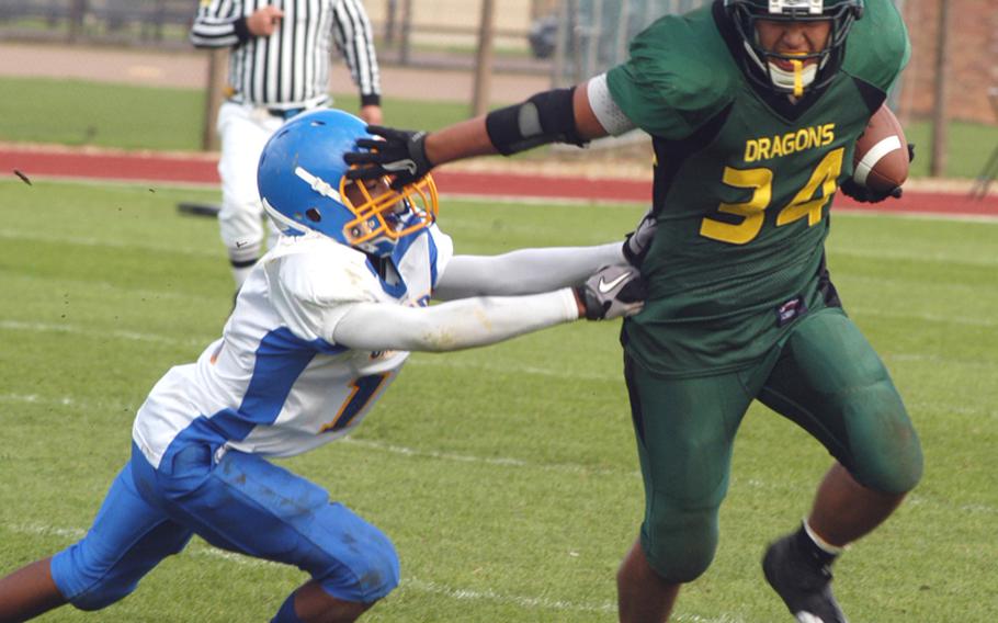 Alconbury's Kerry Kuheana gives a stiff arm to Sigonella defender Marco Montero during a double overtime victory for the Dragons at home on Sept. 25. Kuheana had 296 total yards during the game, won 26-20 by Alconbury but later forfeited by the Dragons for using an ineligible player. The two teams meet again in the Division III championship game.