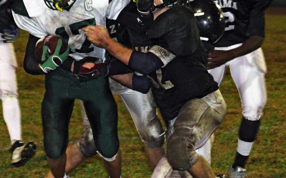 Daegu American Warriors punt returner Ryan Banzon gets a hand in the face of would-be Zama American Trojans coverage man Michael Spencer during Saturday's 2010 Far East High School Division II football championship game at Trojans Field, Zama American High School, Camp Zama, Japan. Daegu won, 28-2.