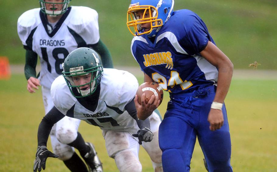 Sigonella's Kahlil Bowen scampers away from Alconbury's Justin Thibodeua, left, and Beau Hocevar. Sigonella jumped out to a 19-0 lad and then held on to beat the Dragons, 19-12, in Baumholder on Saturday, to take the Division III title.