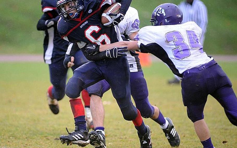 Bitburg's Matt Flood, left, tears himself from the grasp of Mannheim's Chance Bullard for a gain in the Division II title game in Baumholder on Saturday. Bitburg defended its title with a 34-7 win over the Bison.