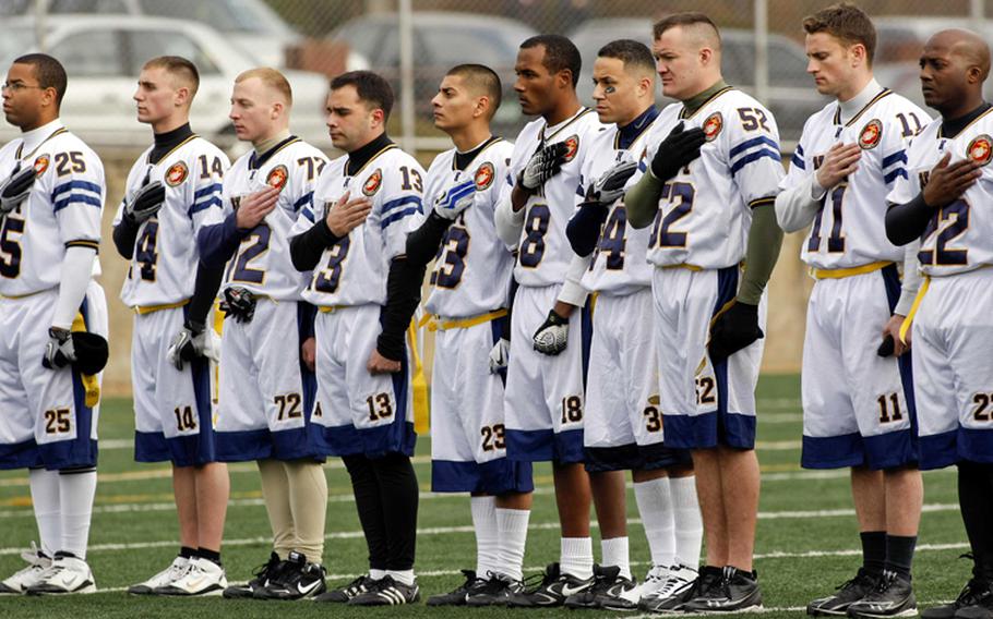 Navy and Marine Corps players pay respects to the colors prior to Saturday's Army-Navy flag football game at Sims Field, Seoul American High School, South Korea. Army prevailed over Navy 12-6 in overtime.