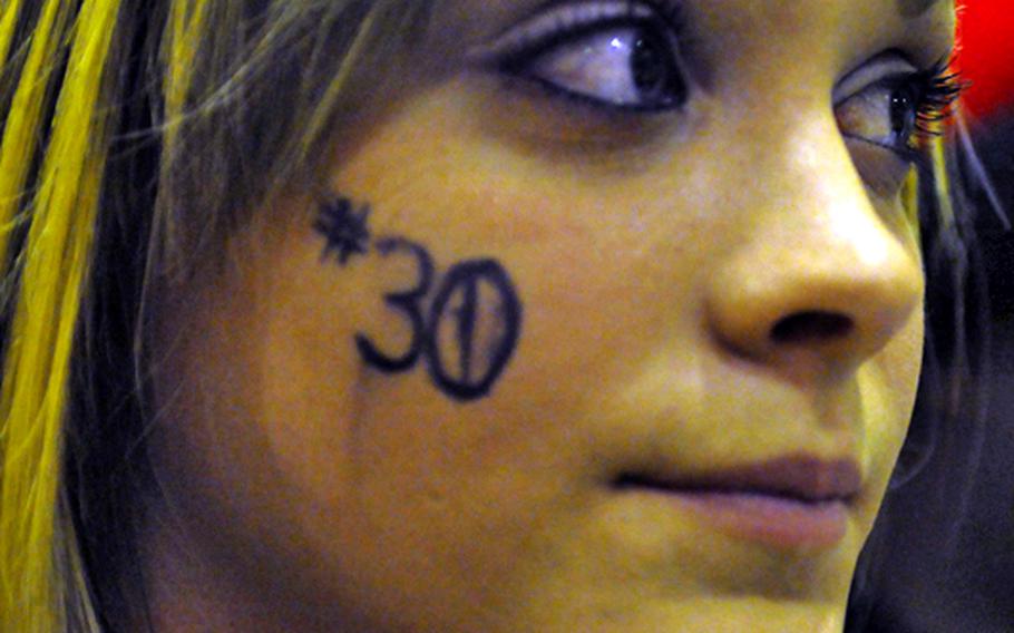 Kadena High School sophomore Rachel Witschen eyes the action, displaying the No. 30 on her right cheek in support of sophomore basketball player Chris Young, during Friday's high school basketball game at Kadena High School, Okinawa. Kadena beat Mirai Tech, 98-62.