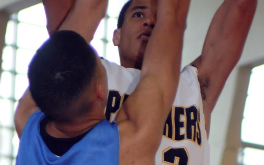 Kadena High School senior Jason Sumpter shoots over U.S. Naval Hospital Camp Lester Bang defender Abraham Bakongo during Saturday's pool play in the 17th Martin Luther King Invitational Basketball Tournament at Camp Foster, Okinawa. Kadena won, 46-34.