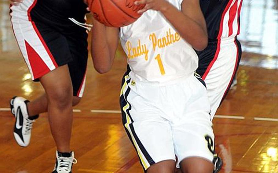 C.C. Daniels of Kadena High School drives to the basket past two Lady Ballaz defenders during Sunday's double-elimination championship bracket game in the 17th Martin Luther King Invitational Basketball Tournament at Camp Foster, Okinawa. Lady Ballaz beat Kadena High, 65-18, hours after the Panthers beat the aircraft carrier USS George Washington, 87-86 in triple-overtime, the highest-scoring women's game in Foster Field House history.