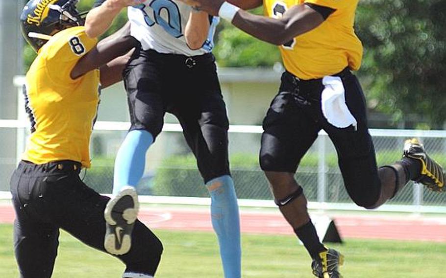 Osan American Cougars receiver Michael Benson hauls in a pass between Kadena Panthers defenders Tyrell Crutcher, left, and Shariff Coleman during an interarea high school football game at Ryukyu Middle School, Kadena Air Base, Okinawa. Interarea football play between DODDS schools in Korea and Okinawa began in September after DODDS officials identified the two areas as ones with need for more regular-season competition. 