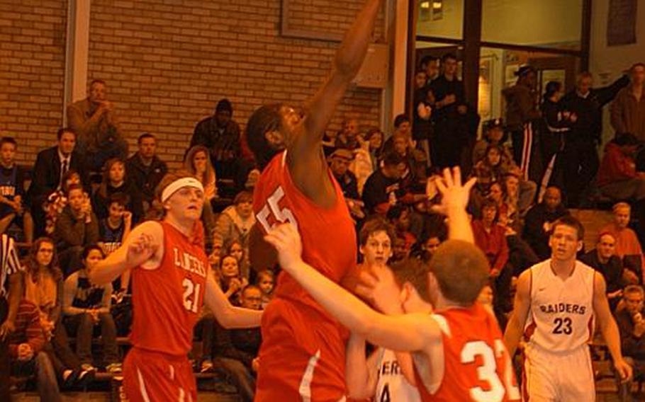 Lakenheath's Brinsely Walker soars above International School of Brussels' Tom White as White tries to get off a shot in ISB's 44-31 victory on Saturday. Lancer defenders Jourden Wilson, right, and Josh Eversman, left, also move in to to shut down White.