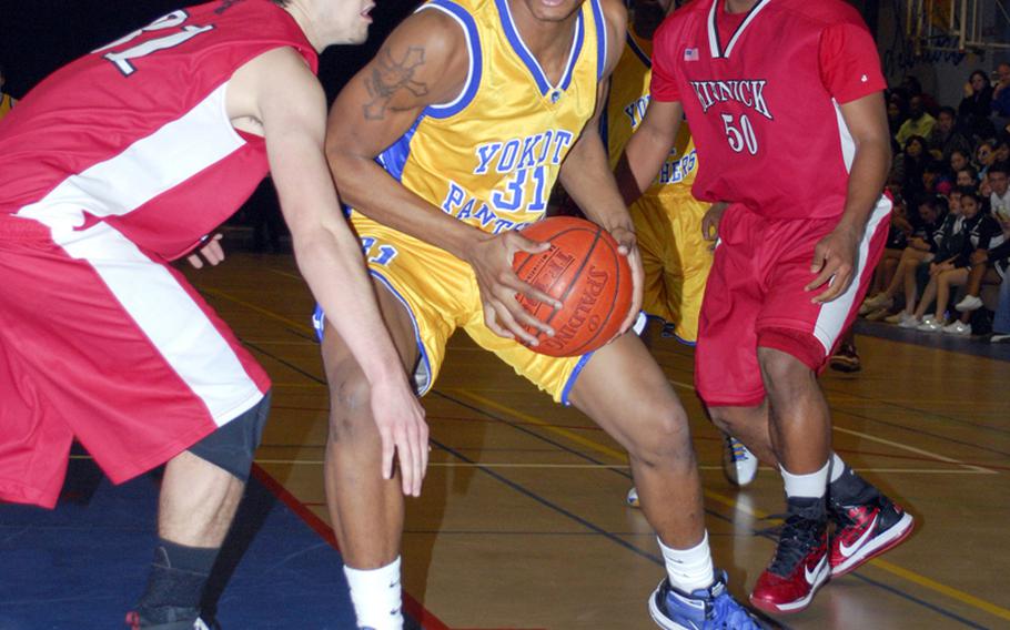 Yokota senior and tournament MVP Myles Andrews finds his path to the basket bottled up by Nile C. Kinnick senior defenders Josh Adair, left, and Ken Haynes during Saturday's boys championship game in the 5th DODDS-Japan basketball tournament at Yokota High School, Japan. Yokota won, 52-33.