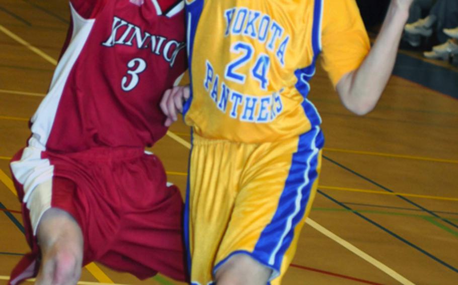 Yokota junior Warren Manegan drives to the basket against Mark Dunphy of Nile C. Kinnick during Saturday's boys championship game in the 5th DODDS- Japan basketball tournament at Yokota High School, Japan. Yokota won, 52-33.