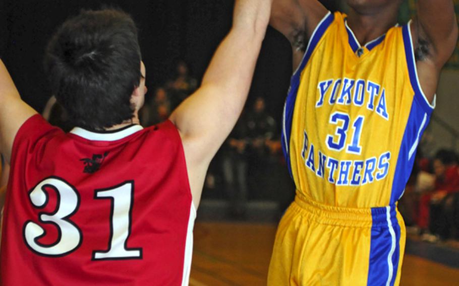 Yokota senior and tournament MVP Myles Andrews shoots over senior Josh Adair of Nile C. Kinnick during Saturday's boys championship game in the 5th DODDS- Japan basketball tournament at  Yokota High School, Japan. Yokota won, 52-33.