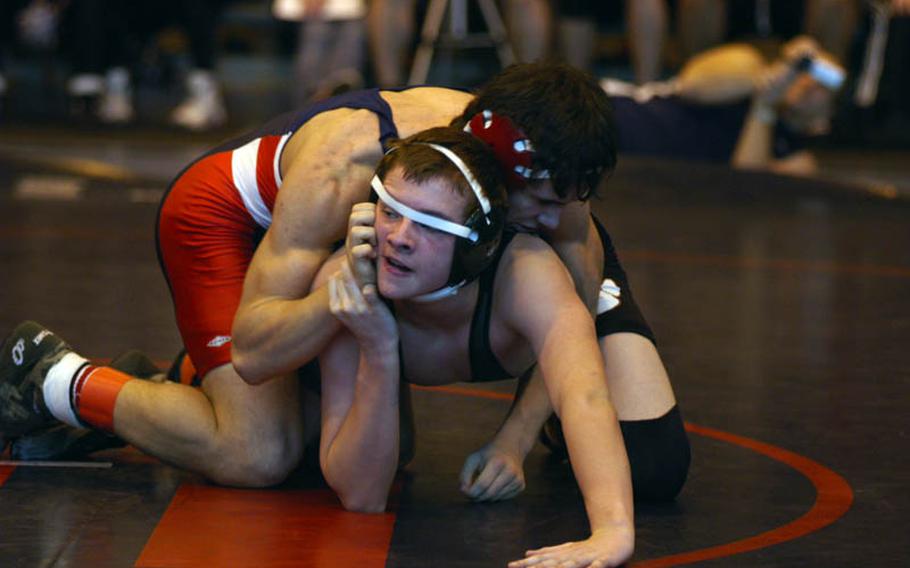 AFNORTH wrestler Aldon Pagio battles Lakenheath's Adam Carrol and a strap from his headgear as he looks to his coaches for advice during a 145-pound bout at the DODDS-Europe Northern Sectionals.