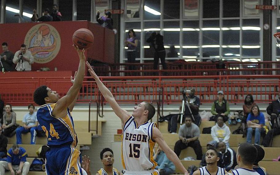 Wiesbaden senior Phillip Tross shoots the ball over the outstretched arm of Mannheim junior Daniel Luckey during Friday night's game at Mannheim's Benjamin Franklin Village Sports Arena. It was the final regular-season game for Mannheim High School, which is closing.